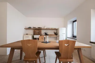 a table and chairs in a room with windows at Gius La Diffusa in Caldaro