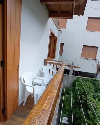 a balcony with white chairs and a wooden table at ROOM AURORA in Fiera di Primiero