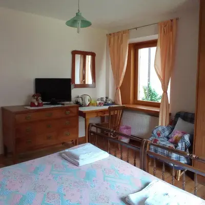 a bedroom with a bed and a desk and a window at ROOM AURORA in Fiera di Primiero