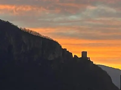 a building on the side of a mountain at sunset at Haus Hafner Sonniges Apartment in Terlano