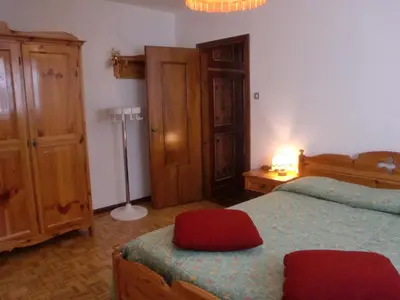 a bedroom with a bed and a dresser and a lamp at Appartamento Niki Campitello in Campitello di Fassa