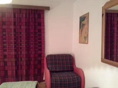 a chair sitting in a room with a red curtain at Appartamento Niki Campitello in Campitello di Fassa