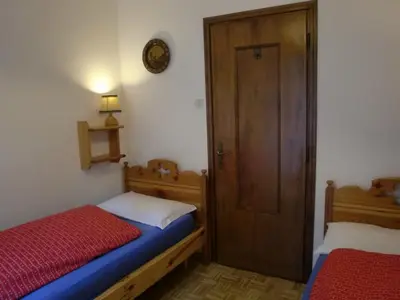 a small bedroom with two beds and a door at Appartamento Niki Campitello in Campitello di Fassa