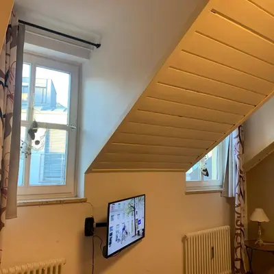 a living room with a tv and two windows at Loft l'Alessandra in Bolzano