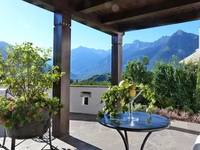 a table on a patio with a view of mountains at Pension Riedingerhof in Merano
