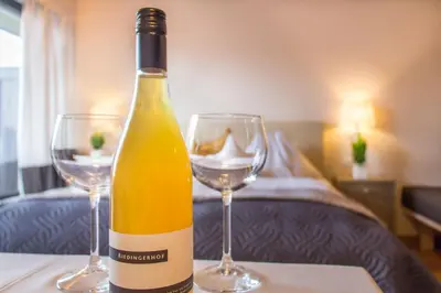 a bottle of wine sitting on a table with two glasses at Pension Riedingerhof in Merano
