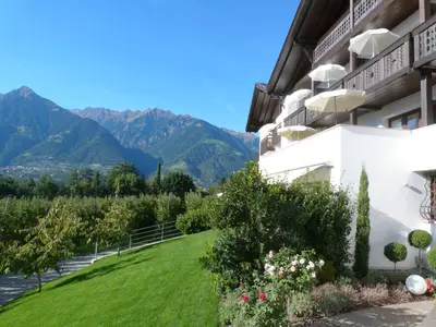 a view from the side of a building with a lawn and mountains at Pension Riedingerhof in Merano