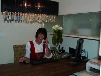 a woman sitting at a desk talking on a phone at Pension Riedingerhof in Merano