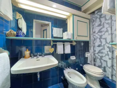 a blue tiled bathroom with a sink and a toilet at I cuori in Cortina dʼAmpezzo