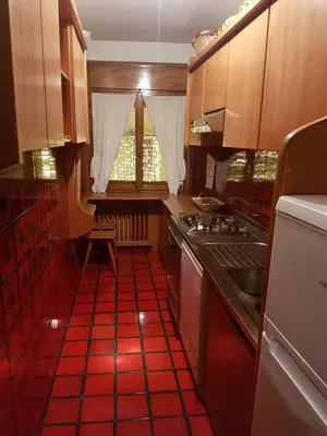 a kitchen with a red tiled floor and a sink at I cuori in Cortina dʼAmpezzo