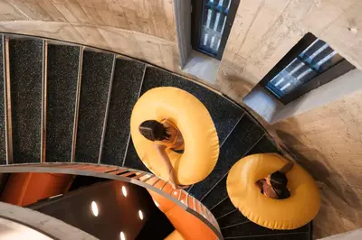 an overhead view of a spiral staircase with two people on inflatables at AKI Family Resort PLOSE in Bressanone