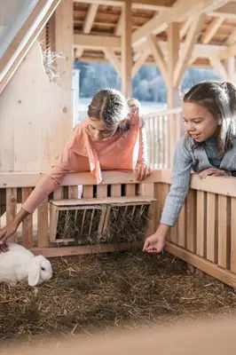 two young girls are looking at a chicken cage at AKI Family Resort PLOSE in Bressanone