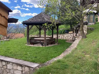 a wooden gazebo with a bench in the grass at CASA BAMBA in Tesero