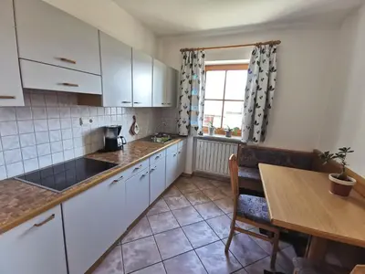 a kitchen with white cabinets and a table and a window at Rastenfeldhof in Parcines