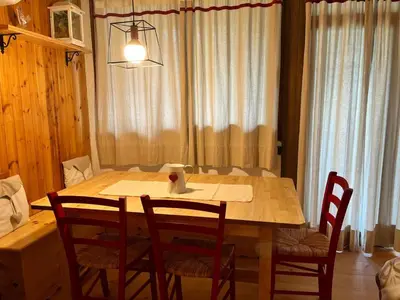 a dining room table with four chairs and a table and a candle at Appartamento Al Laghetto in San Martino di Castrozza