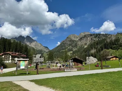 a park with a playground with mountains in the background at Appartamento Al Laghetto in San Martino di Castrozza