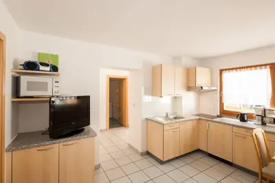 a kitchen with wooden cabinets and a tv in it at Appartements Kirchtalhof in Lana