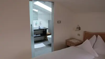 a bedroom with a bed and a bathroom with a mirror at Appartements Kirchtalhof in Lana