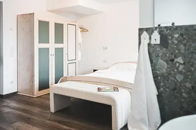 a bedroom with a bed with a bench next to it at Wolter Landhaus in Vipiteno