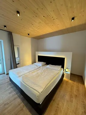 a large bed in a bedroom with a wooden ceiling at Lindenhof Residence Meran in Merano