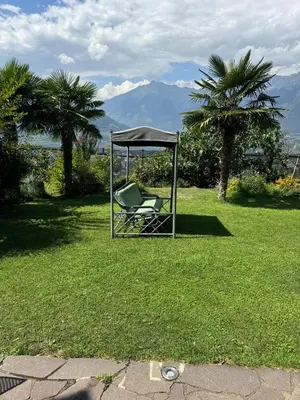 a chair sitting under a gazebo in a yard at Lindenhof Residence Meran in Merano