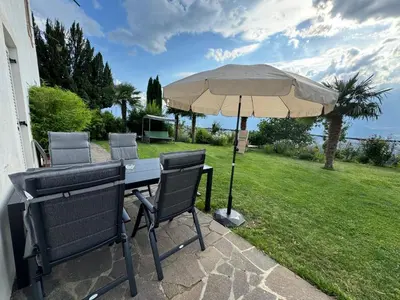 a table and chairs with an umbrella on a lawn at Lindenhof Residence Meran in Merano