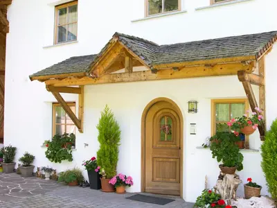 a wooden door on a white house with potted plants at Oberbaumgartnerhof in Falzes