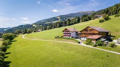 an aerial view of a house on a green hill at Oberbaumgartnerhof in Falzes