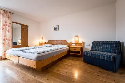 a bedroom with a bed and a couch and a chair at Oberbaumgartnerhof in Falzes