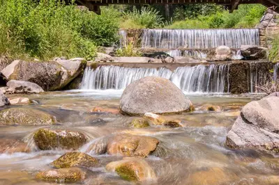 a stream of water with rocks and a waterfall at Agritur Artemisia in Tesero