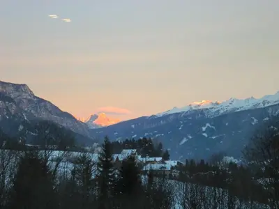 a sunset over the mountains with a house in the foreground at Casa Erica - Carano in Carano