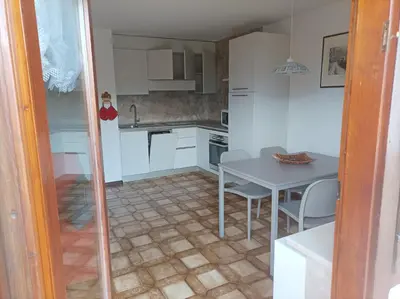 a kitchen with white cabinets and a table and chairs at Casa Erica - Carano in Carano