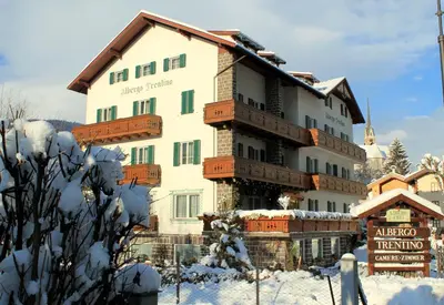 a large building in the snow with a sign in front at Albergo Trentino in Moena