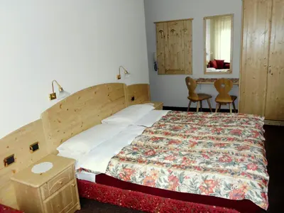 a bedroom with a bed and a table and chairs at Albergo Trentino in Moena