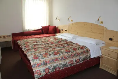 a bedroom with a large bed with a floral bedspread at Albergo Trentino in Moena