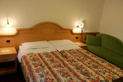 a bedroom with a bed and a green couch at Albergo Trentino in Moena