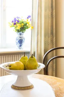 a plate of pears on a table with a vase at Gasthof zur Krone in Aldino