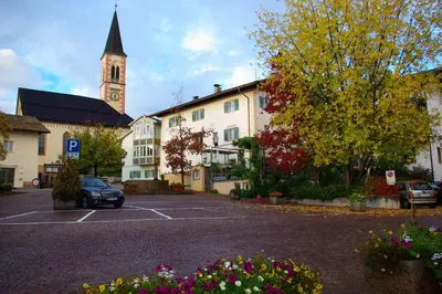 a parking lot in front of a building with a clock tower at Gasthof zur Krone in Aldino