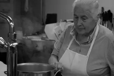 a woman in a kitchen preparing food in a pot at Gasthof zur Krone in Aldino