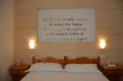 a bedroom with a large bed and a whiteboard on the wall at Garnì Valdan in Falcade