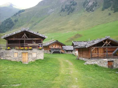 a group of buildings in a field with a mountain at La Casa di Sofia in Alleghe