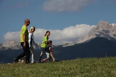 a family walking on a hill with mountains in the background at La Casa di Sofia in Alleghe