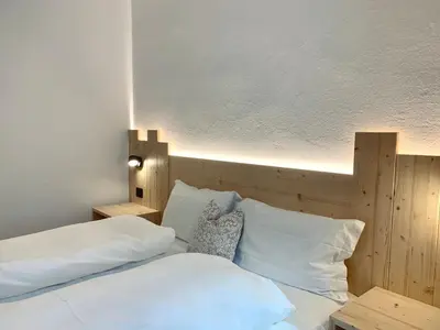 a bedroom with a bed with white sheets and pillows at Cesa Do Ruf eurochalet in Campitello di Fassa