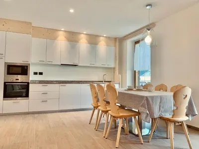 a kitchen with white cabinets and a table and chairs at Cesa Do Ruf eurochalet in Campitello di Fassa