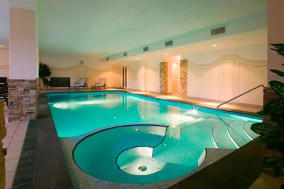 a large swimming pool in a building with a pool at Hotel Schönbrunn in Schenna
