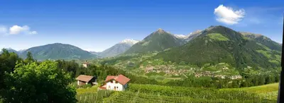 a village in a valley with mountains in the background at Hotel Schönbrunn in Schenna