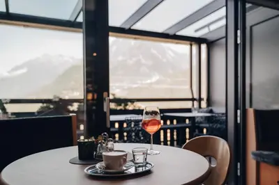 a glass of wine sitting on a table with a view at Hotel Schönbrunn in Schenna
