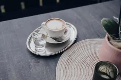 a cup of coffee and a glass of water on a table at Hotel Schönbrunn in Schenna