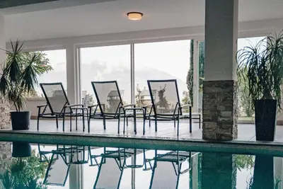 a group of chairs sitting around a swimming pool at Hotel Schönbrunn in Schenna