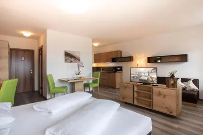 a bedroom with two beds and a kitchen and a table at Hotel Schönbrunn in Schenna